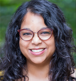 a smiling person wearing glasses and a yellow top